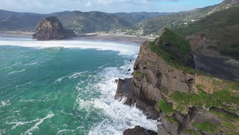 Piha-Beach---Strong-Waves-Crashing-Against-The-Nun-Rock-And-Taitomo-Island-In-Auckland,-New-Zealand