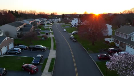 Slow-flight-over-neighborhood-with-parking-cars-in-USA-at-sunset-time