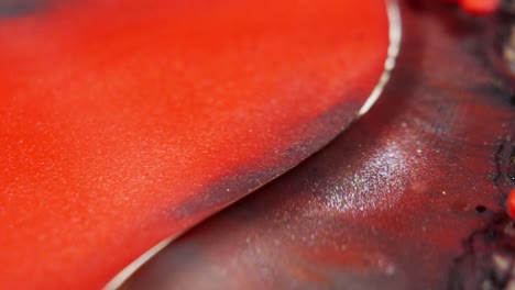 Close-up-shot-of-vibrant-red-ink-diffusing-in-water,-creating-abstract-patterns