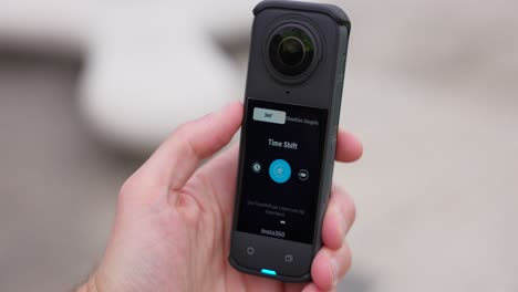 Insta360-X4-Actionkamera-In-Der-Hand-Halten-Und-über-Den-Touchscreen-Kameraoptionen-Auswählen