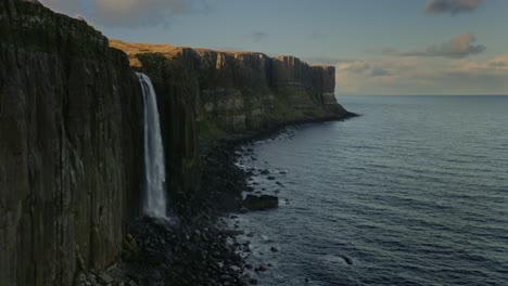 Up-close-dolly-in-panoramic-flight-reveals-the-Kilt-Rock-Waterfall,-Isle-of-Skye,-Scotland