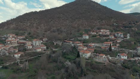 Drohnen-Zoom-Out-Flug-über-Einem-Dorf-Auf-Einem-Hohen-Hügel,-Rote-Dächer,-Kleine-Häuser,-Malerische-Berge,-Griechenland,-4K-Video