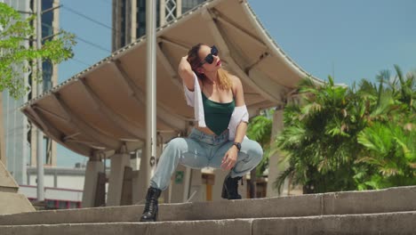 Exploring-a-Caribbean-cityscape,-a-girl-in-jeans-and-boots-meanders,-while-tall-buildings-loom-in-the-background