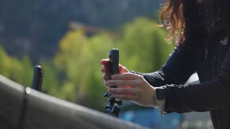 Woman-attaches-action-camera-to-a-tripod-or-suction-mount-before-shooting-video