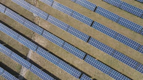 Expansive-solar-farm-capturing-sustainable-energy-on-a-sunny-day,-overhead-shot,-aerial-view