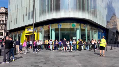 In-London's-Leicester-Square,-visitors-patiently-line-up-for-entry-into-the-M-And-M's-store,-embodying-the-spirit-of-anticipation-and-excitement-for-a-playful-and-immersive-experience