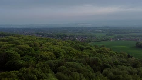 Luftaufnahme-Der-Baumkronen-Des-Waldes-In-Richtung-Der-Landschaft-Von-Lancashire-Und-Der-Winter-Hill-Mountain-Range