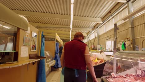 Female-butcher-going-behind-counter-in-old-retro-market-place-in-the-Baltics