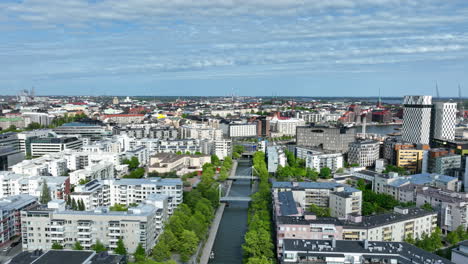 Vista-Aérea-Hacia-Atrás-Sobre-El-Canal-Y-El-Parque-Ruoholahti,-Día-De-Primavera-En-Helsinki