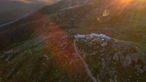 Beautiful-Thredbo-ski-resort-chairlift-aerial-in-summer-off-season-with-sunrise-lens-flare-in-Snowy-Mountains,-NSW,-Australia