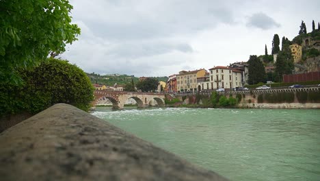 Scenic-static-shot-of-river-flowing-underneath-the-Ponte-Pietra-in-Verona,-Italy