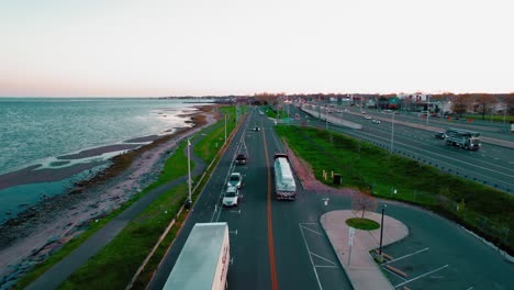 Red-semi-truck-with-flatbed-trailer-driving-at-sunset-in-New-Haven,-Connecticut,-USA