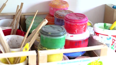Close-up-of-paint-containers,-brushes,-other-art-supplies-in-small-game-factory