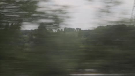 Paisaje-Borroso-Desde-La-Ventana-De-Un-Tren-Que-Muestra-El-Bosque-Y-Los-Autos-Que-Pasan,-Efecto-De-Desenfoque-De-Movimiento