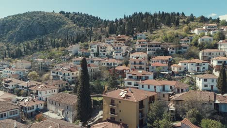 Drones-Volando-Hacia-Arriba,-Sobre-Un-Pueblo-En-Una-Colina-Verde-En-Europa,-Tejados-Rojos,-Casitas,-Clima-Soleado,-Video-Grecia-4k