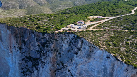 Navagio-pludmale-hotel-buildings-on-edge-of-escarpment-looking-down-white-cliff