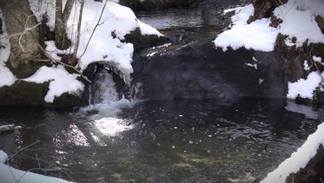 Un-Arroyo-Nevado-Fluye-Sobre-Rocas-En-Cámara-Lenta