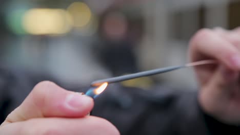 Close-up-of-a-sparkler-igniting,-with-vivid-sparks-and-a-blurred-background