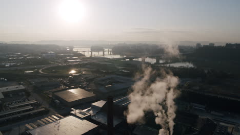 Aerial-footage-of-the-smoke-coming-off-of-a-factory-with-downtown-Chattanooga,-TN-in-the-background