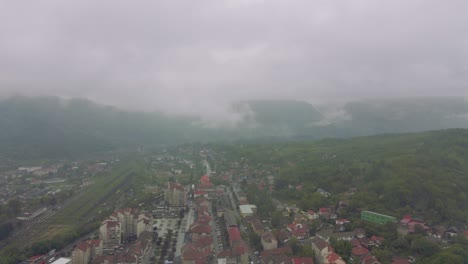 4K-Filmmaterial-Aus-Der-Luft-Mit-Drohnen,-Die-Bei-Regen-In-Der-Stadt-In-Den-Regenwolken-Fliegen,-Mit-Bergen-Im-Hintergrund