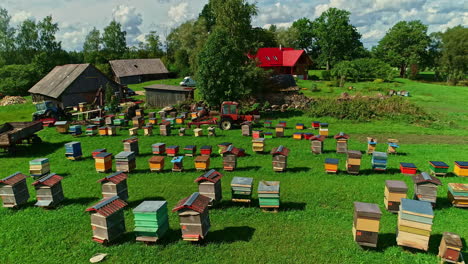 Colorful-Beehives-and-Farm-in-Green-Farming-Land-on-Sunny-Day,-Drone-Shot