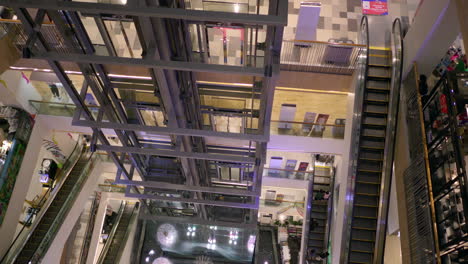 Elevators-and-escalators-moving-up-and-down-inside-a-shopping-center-in-the-middle-of-Bangkok,-in-Thailand