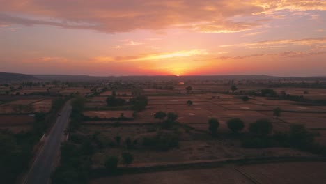 Toma-Aérea-De-Drones-De-Hermosas-Nubes-Al-Atardecer-Sobre-El-Horizonte-Y-Granjas-De-Trigo-En-Un-Pueblo-Rural-Del-Norte-De-La-India