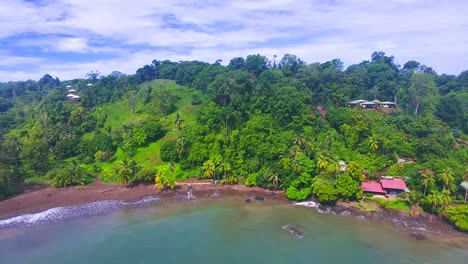 Aerial-video-sliding-along-the-coast-of-a-lush-green-island-village-at-Drake-Bay-in-Costa-Rica-during-raining-season