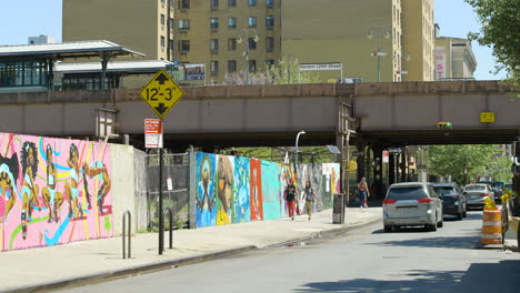 La-Gente-Pasa-Por-Arte-Colorido-En-La-Valla-De-Un-Terreno-Baldío-En-Harlem,-Nueva-York