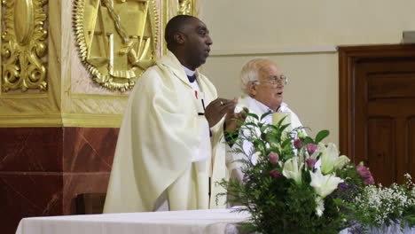 Zwei-Priester-Halten-Einen-Gottesdienst-In-Einer-Kirche,-Geschmückt-Mit-Einem-Goldenen-Altar-Und-Frischen-Blumen,-Ein-Moment-Der-Spanischen-Kommunion