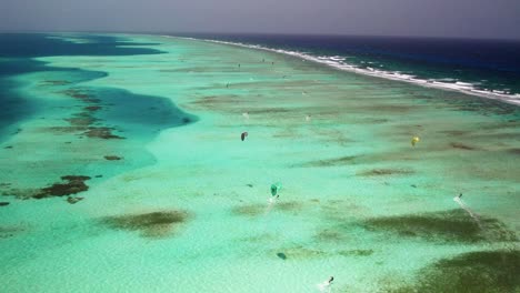 Kitesurfistas-En-Aguas-Turquesas-En-La-Barrera-De-Coral-De-Los-Roques,-Vibrante-Y-Pintoresca,-Vista-Aérea