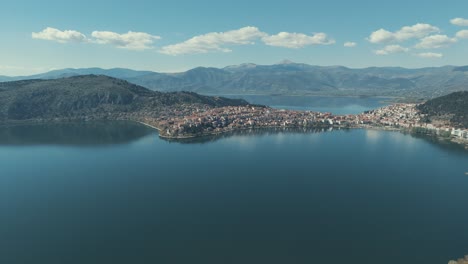 Drone-EPIC-FLIGHT-above-a-village-on-a-hill-in-Europe,-red-roof-tops,-little-houses,-sunny-weather,-blue-water-lake,-SCENIC-mountains,-Greece-4K-video