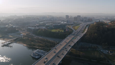 Breite-Luftaufnahmen-Des-Dichten-Verkehrs-Auf-Der-Williams-Memorial-Bridge-Auf-Dem-Highway-27-In-Chattanooga,-Tennessee-Mit-Der-Innenstadt-Im-Hintergrund-Bei-Sonnenaufgang