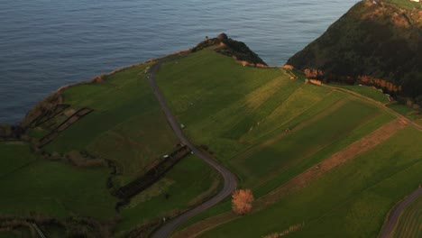 Drone-footage-of-lush-green-volcanic-island-country-ocean-cliffs-with-steam-from-hot-spring-rising-on-the-Azores-Sao-Miguel-Island