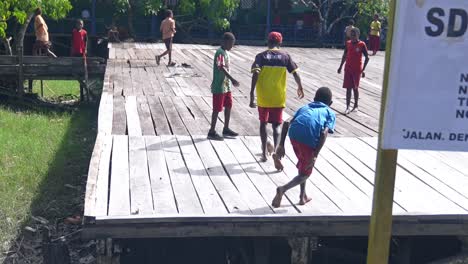 Children-play-football-soccer-in-wooden-deck-pitch-undeveloped-area-Indonesia