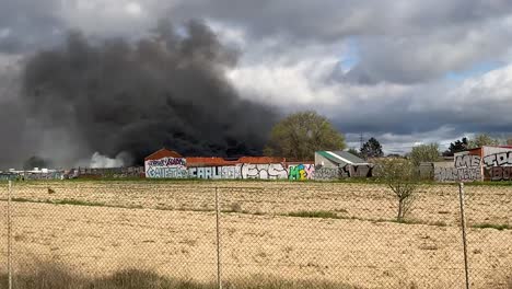 From-a-vehicle-we-see-a-large-fire-that-occurred-in-Leganes-Madrid,-with-the-fire-and-police-forces-fully-acting,-their-vehicles-are-parked-and-we-see-a-firefighter-putting-out-the-fire