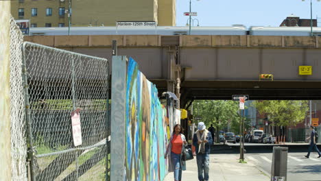 Menschen-Gehen-An-Einem-Unbebauten-Grundstück-In-Harlem,-New-York,-Vorbei,-über-Dem-Ein-Zug-Vorbeifährt