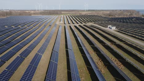 Expansive-solar-farm-on-a-clear-day,-capturing-rows-of-photovoltaic-panels,-aerial-view