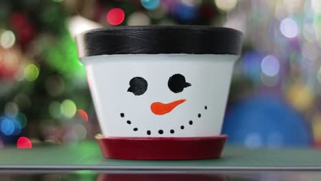 Snowman-themed-flower-pot-with-festive-Christmas-motifs-and-twinkling-lights
