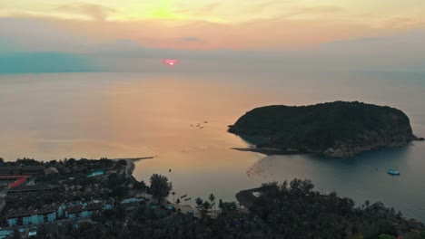 Toma-Aérea-De-Un-Dron-De-Una-Puesta-De-Sol-Sobre-Una-Isla-Costera-Y-Un-Pueblo-En-Tailandia