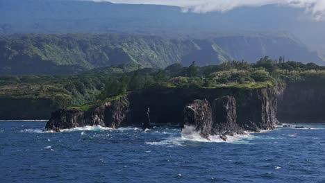 Rugged-cliffs-of-Maui's-North-Shore-along-the-scenic-Road-to-Hana,-lush-greenery-in-the-background