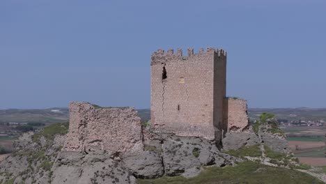 Aufsteigender-Flug-Mit-Einer-Drohne-über-Die-Oreja-Burg-Aus-Dem-9.-Jahrhundert-Im-Vordergrund,-Beginnend-Mit-Einem-Blauen-Himmel-Im-Hintergrund-Und-Entdecken-Sie-Einige-Getreidefelder-Durch-Eine-Kamera,-Biegen-Sie-Auf-Tigola-Toledo-Spanien-Ab