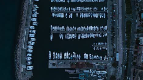 Twilight-aerial-view-of-Menton-marina-on-the-French-Riviera,-showcasing-neat-rows-of-moored-boats