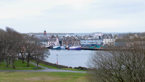 Scenic-landscape-view-from-Lews-Castle-overlooking-Stornoway-town-and-harbour-water,-moored-boats-and-ships,-and-town-houses,-shops,-and-businesses-in-the-Outer-Hebrides-of-Scotland-UK