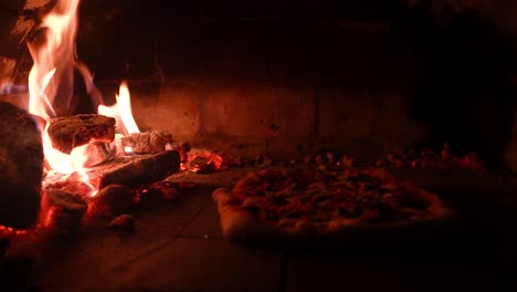 Pizza-Recién-Horneada-En-Un-Tradicional-Horno-De-Leña,-Brasas-Brillantes-Y-Una-Cálida-Iluminación-Ambiental