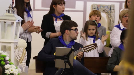 Guitarrista-Actuando-En-Una-Ceremonia-De-Comunión-Española,-Rodeado-De-Niños-Y-Adultos-Atentos.