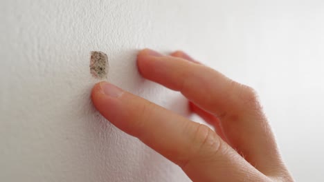 Man-inspecting-a-damage-in-a-plastered-wall-with-his-fingers