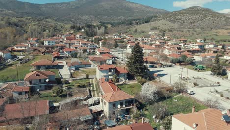 Drone-flight-backwards,-above-a-village-in-Europe,-green-hills,-red-roof-tops,-little-houses,-4K-video