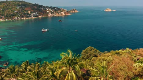 Aerial-drone-shot-capturing-a-Tropical-Island-bay-view-with-boats-on-clear-turquoise-blue-water-in-Thailand