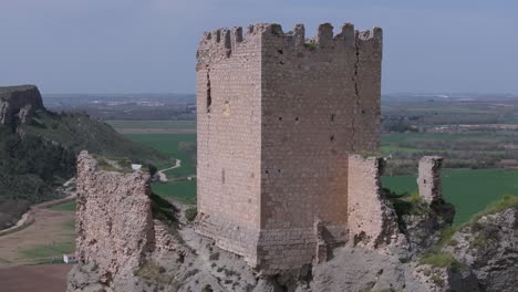 Prächtiger-Rückzugsflug-In-Der-Burg-Von-Oreja-Aus-Dem-9.-Jahrhundert,-Nahaufnahme-Des-Bergfrieds-Und-Der-Mauerreste-Vor-Dem-Hintergrund-Kultivierter-Felder,-Wir-Sehen-Die-Lage-Der-Festung-Ontigola